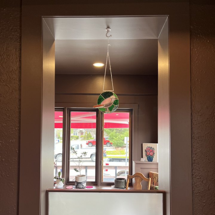 <i>Untitled</i>. An image of a stained glass rendition of the logo of Pink Crow Cafe, hanging up in the cafe.